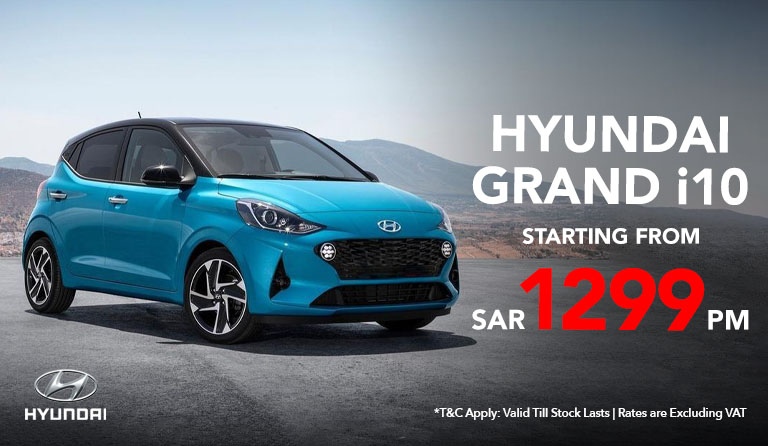A blue Hyundai Grand i10 car is parked on a mountain road with a scenic background. Text: "Hyundai Grand i10 starting from SAR 1299 PM."